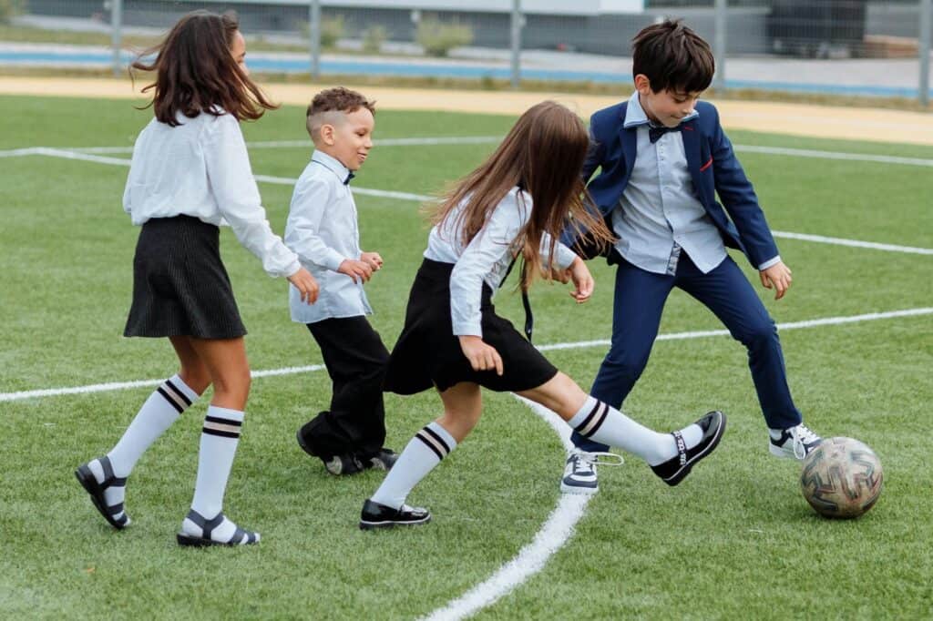 Young students are playing football in the school's field
