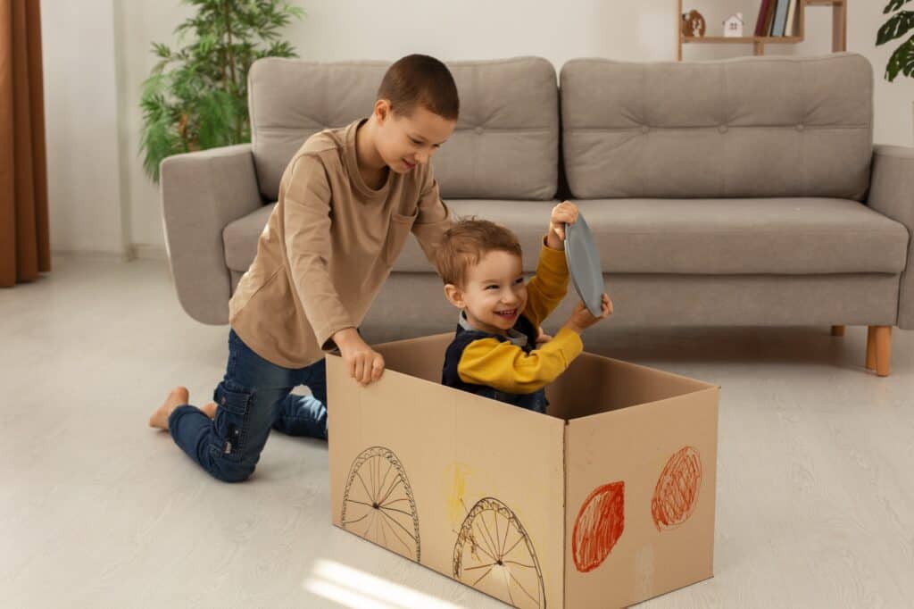 Two brothers playing with a box transformed into a toy car