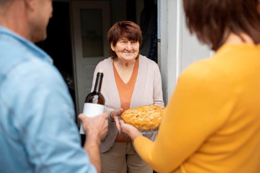 Cropped image of a couple sharing food and wine with their new neighbour