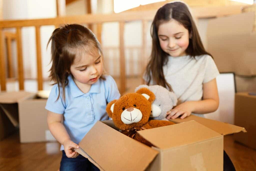 Little girls packing stuffed animals into a carton